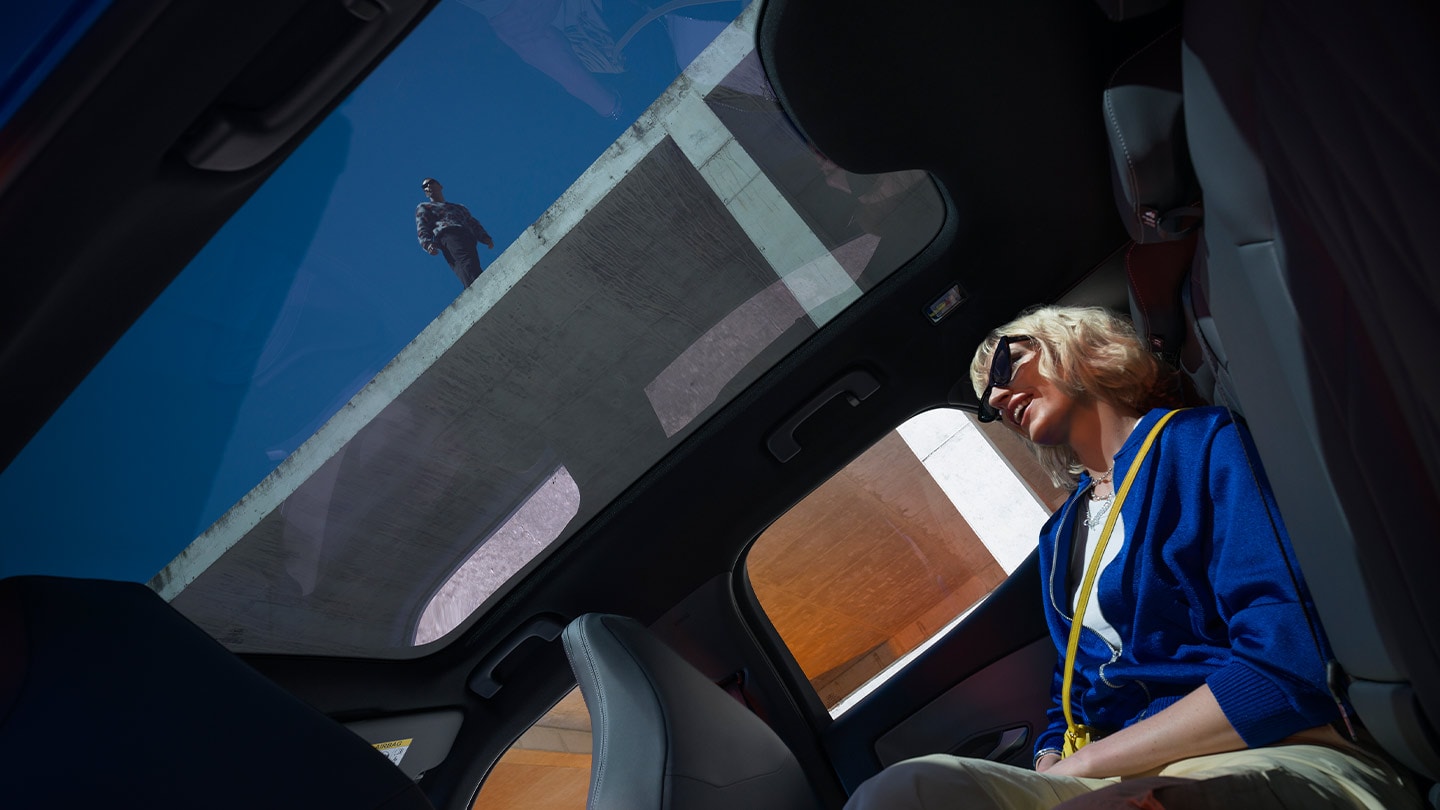 Person sitting inside the new Ford Capri® enjoying the panoramic glass roof.